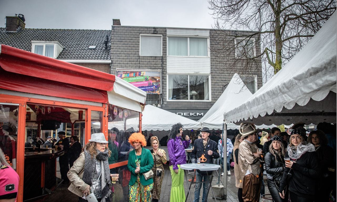 Bezoekers met een drankje rond de Schirmbar op een plein